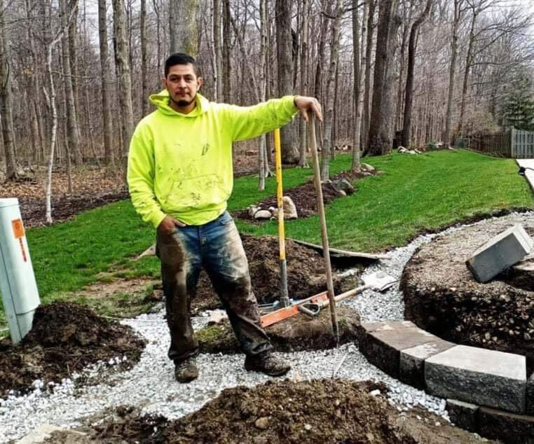 Professional landscaper working on a residential project in Indianapolis, featuring modern landscaping tools, and highlighting the transformation of a garden area.